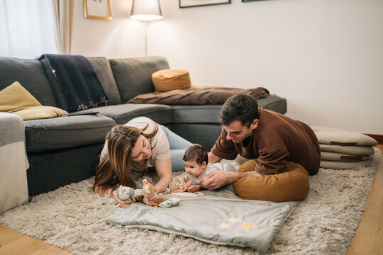 Parents playing with baby on living room rug