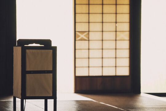 和室に置かれた伝統的な行灯のシルエットと光を透かす障子のノスタルジックな風景,
