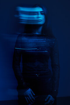 Woman in blue light with blurred motion effects in dark setting