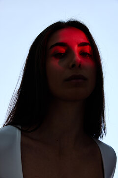 Woman with long hair stands against blue sky with red light on f