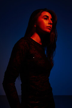 Woman standing against blue background with soft light at night