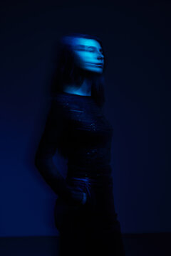 Model poses in blue light with a dark background during a photos