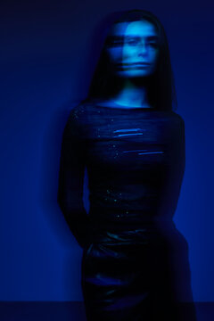 Model stands against blue background in a blurred moment