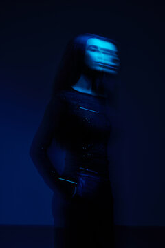 Model poses in blue light with motion blur at a studio