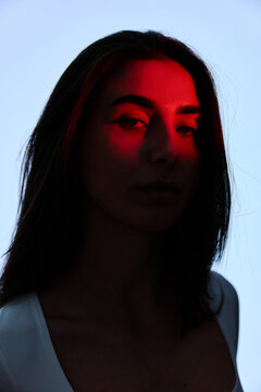 Woman with dramatic lighting poses against a blue sky