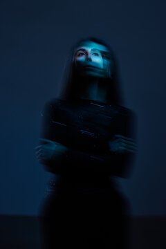 Woman standing in dark room with blue light at night