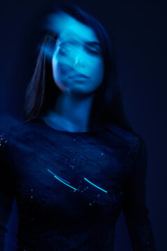 Woman with blurred movement under blue light in dark setting