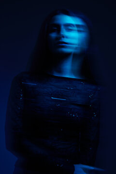 Woman standing still in blue light with motion blur effects