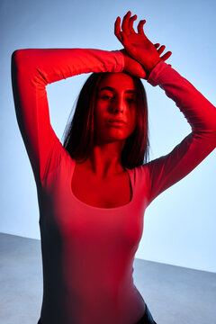 Model poses with hands raised in a red-lit studio setting