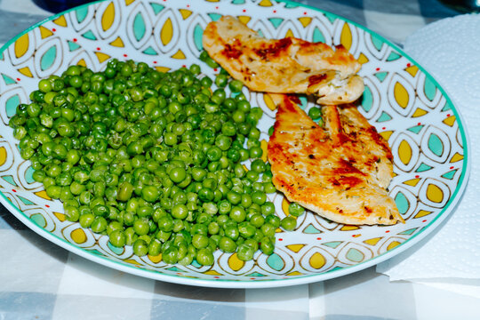 green peas and grilled chicken breast fillets on a ceramic dish
