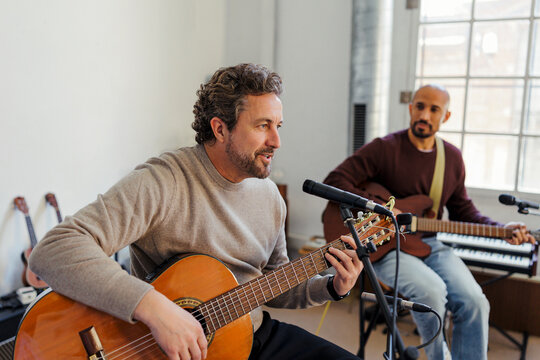 Musician singing into microphone playing acoustic guitar