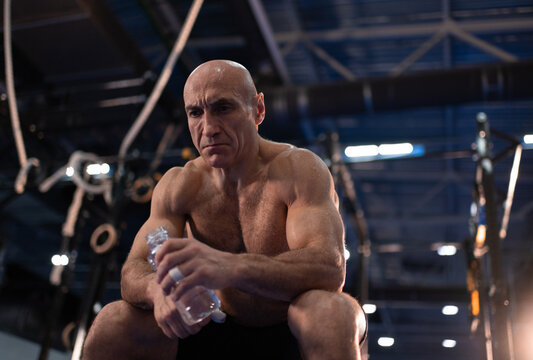 Exhausted senior sportsman with water resting during training