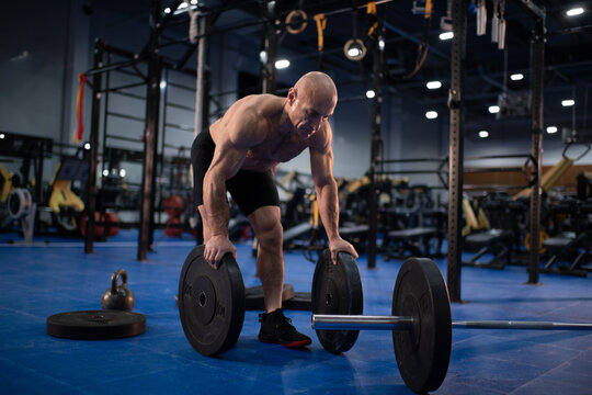 Muscular male senior athlete preparing barbell for training