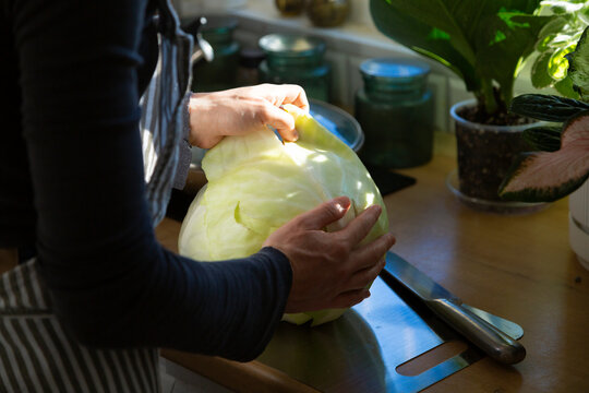 Woman preparing fresh white cabbage for cooking