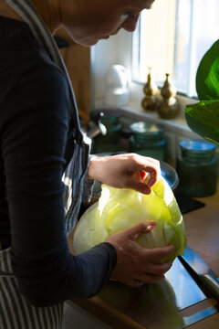 Woman preparing fresh cabbage in sunny kitchen
