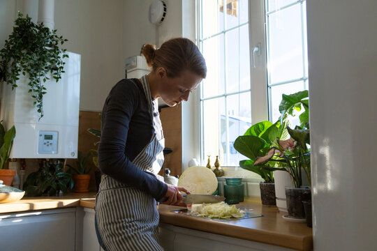 Woman chopping white cabbage preparing healthy meal in kitchen
