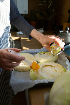 Woman preparing cabbage steaks with olive oil