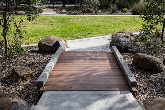 A pedestrian footbridge spans a stormwater drainage swale in a community park. Designed for sustainable urban water management. Sustainable urban water management with aesthetic features in Australia