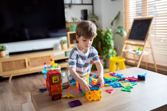 Young boy building magnetic tiles in living room