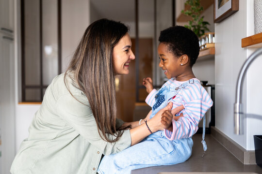 Mother and adopted daughter bonding in kitchen