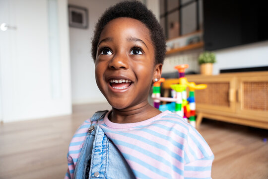Happy black child looking up and smiling at home