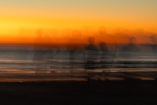 Artistic motion blur of people walking on the beach at sunset
