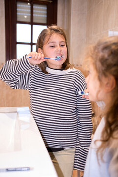 Children brushing teeth in bathroom mirror reflection