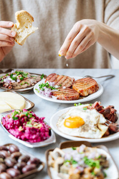 Person squeezing lemon over grilled meat with assorted dishes