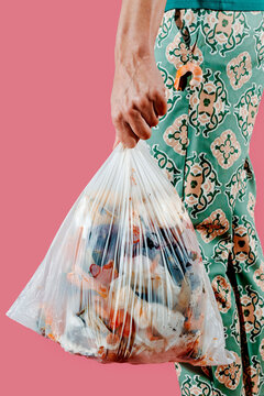 a man carries a compostable trash bag filled with food waste