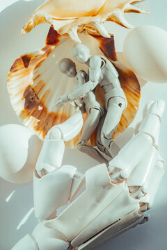 Figures interact with seashell and eggs in still life setting