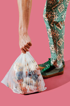 lifts a compostable trash bag with food waste from the ground