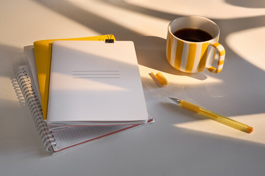 Notebooks and Coffee Cup on White Table During Afternoon