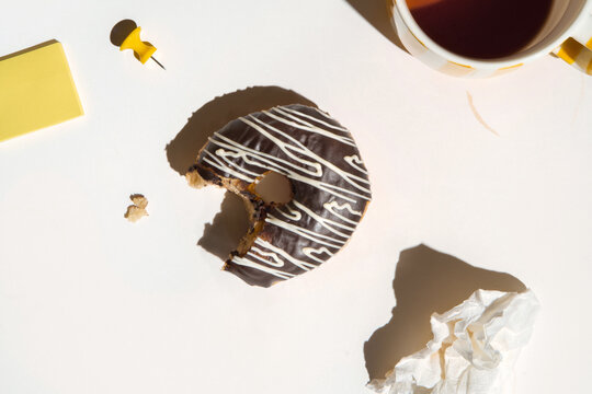 Enjoying Chocolate Donut on a White Office Desk with Copy Space.