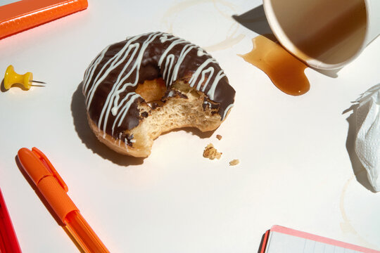 Donut With Bite Taken on a Table With Coffee Spill and Copy Space.