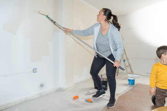 Woman painting wall with roller during home renovation