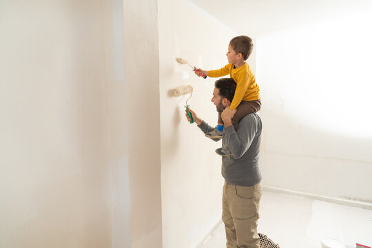 Father and son painting wall during home renovation