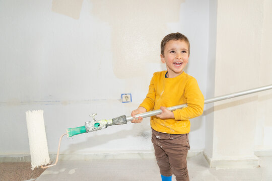 Happy boy helping with home renovation painting wall
