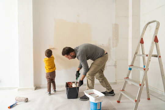 Father and son painting wall during home renovation