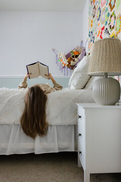Girl reading a book on her bed