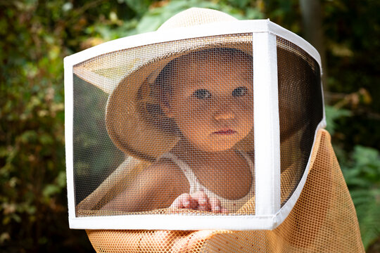 little girl wearing a bee-keeping hat in the forest