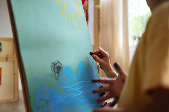 Child Painting On Large Blue Canvas In Studio