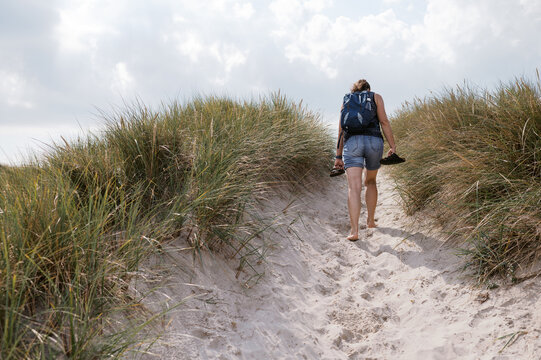 middle aged woman walking across dunes in Denmark 