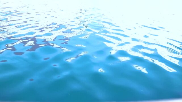 Water background, ripples and flow with waves. Blue swimming pool surface pattern exposed to sunlight. Blank space for text.