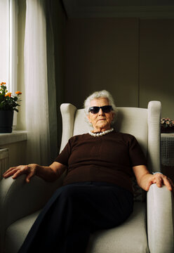 Portrait of a stylish senior woman itting on an armchair in her living