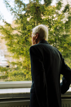 Senior man looking outside window