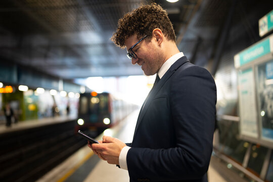 Man checks phone at train station
