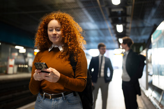 Woman checks phone on subway

