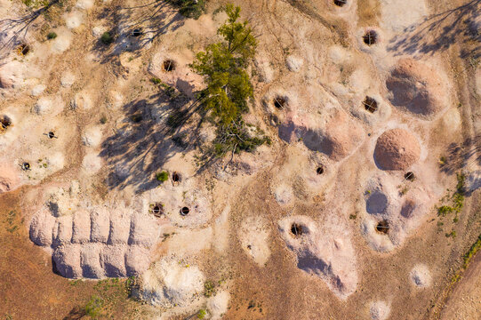 Dirt piles alongside opal mining holes in an arid outback landscape
