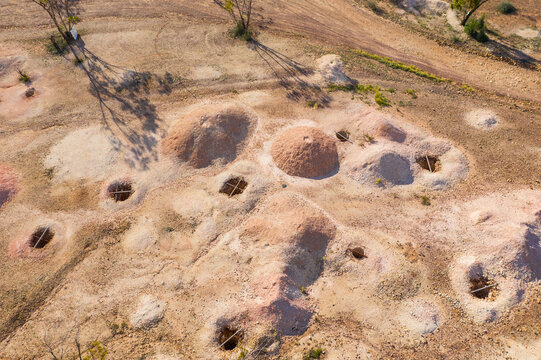 Dirt piles alongside opal mining holes in an arid outback landscape