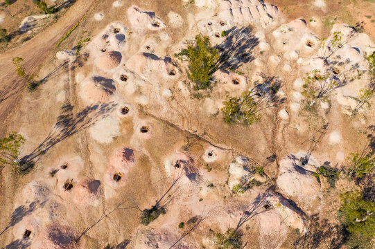 Dirt piles alongside opal mining holes in an arid outback landscape
